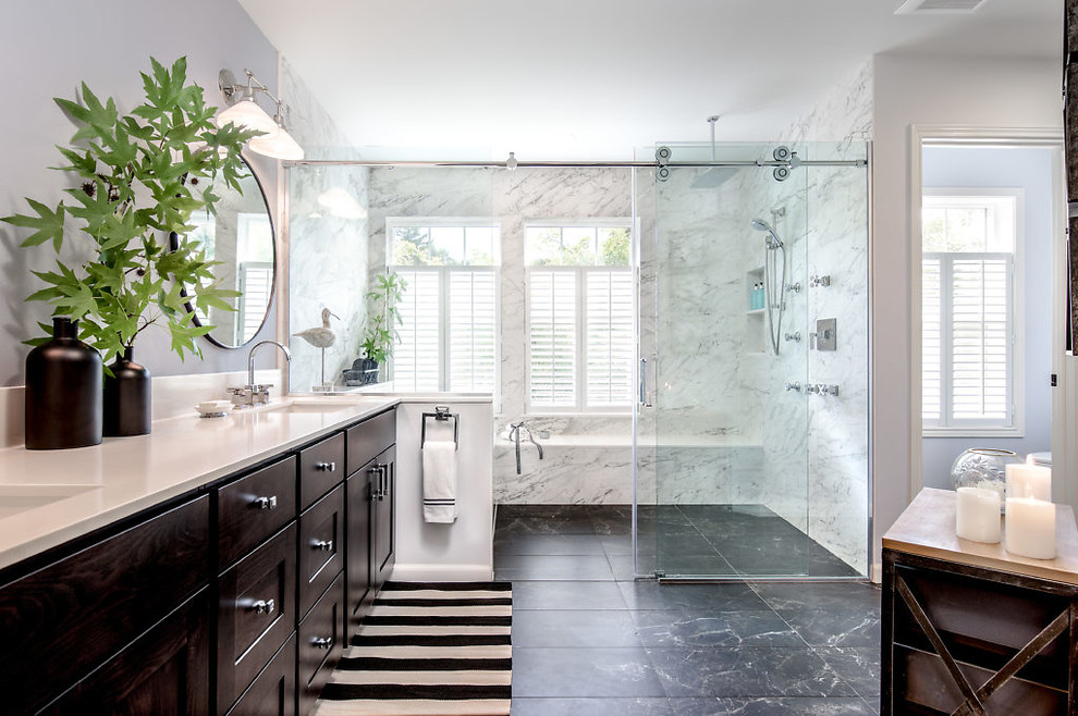 This is an example of a large contemporary master wet room bathroom in Seattle with recessed-panel cabinets, dark wood cabinets, engineered quartz benchtops, white benchtops, an alcove tub, grey walls, marble floors, an undermount sink, black floor and a sliding shower screen.