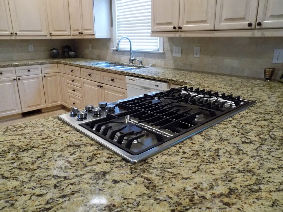 Kitchen - large transitional u-shaped porcelain tile kitchen idea in Atlanta with a triple-bowl sink, raised-panel cabinets, light wood cabinets, granite countertops, beige backsplash, stone tile backsplash, stainless steel appliances and a peninsula