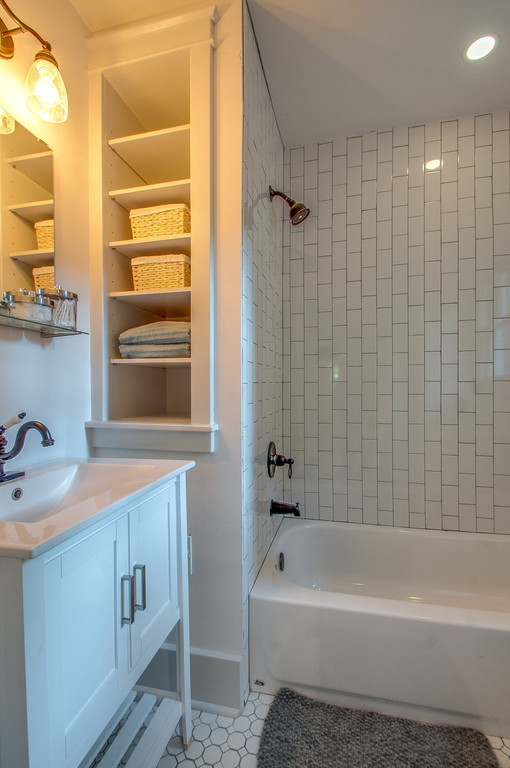 This is an example of a small arts and crafts bathroom in Nashville with an integrated sink, shaker cabinets, white cabinets, engineered quartz benchtops, an alcove tub, a shower/bathtub combo, a two-piece toilet, white tile, subway tile, white walls and ceramic floors.