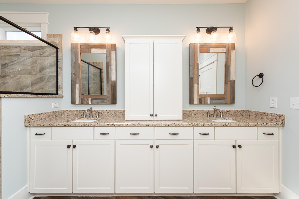 This is an example of a mid-sized traditional master bathroom in Raleigh with shaker cabinets, white cabinets, an alcove shower, a two-piece toilet, white tile, ceramic tile, blue walls, vinyl floors, an undermount sink, granite benchtops, brown floor, a hinged shower door, multi-coloured benchtops, an enclosed toilet, a single vanity and a built-in vanity.