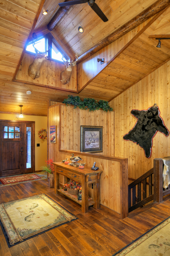 Example of a mountain style medium tone wood floor foyer design with yellow walls and a dark wood front door