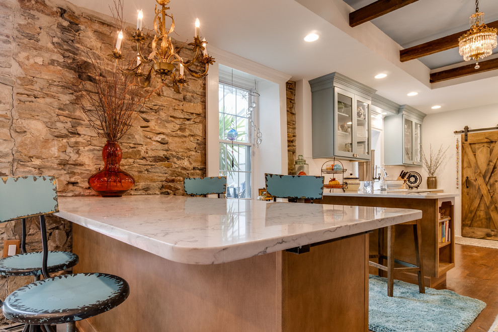 Photo of a large country l-shaped separate kitchen in Philadelphia with glass-front cabinets, blue cabinets, quartzite benchtops, white splashback, white appliances, dark hardwood floors, a peninsula and white benchtop.