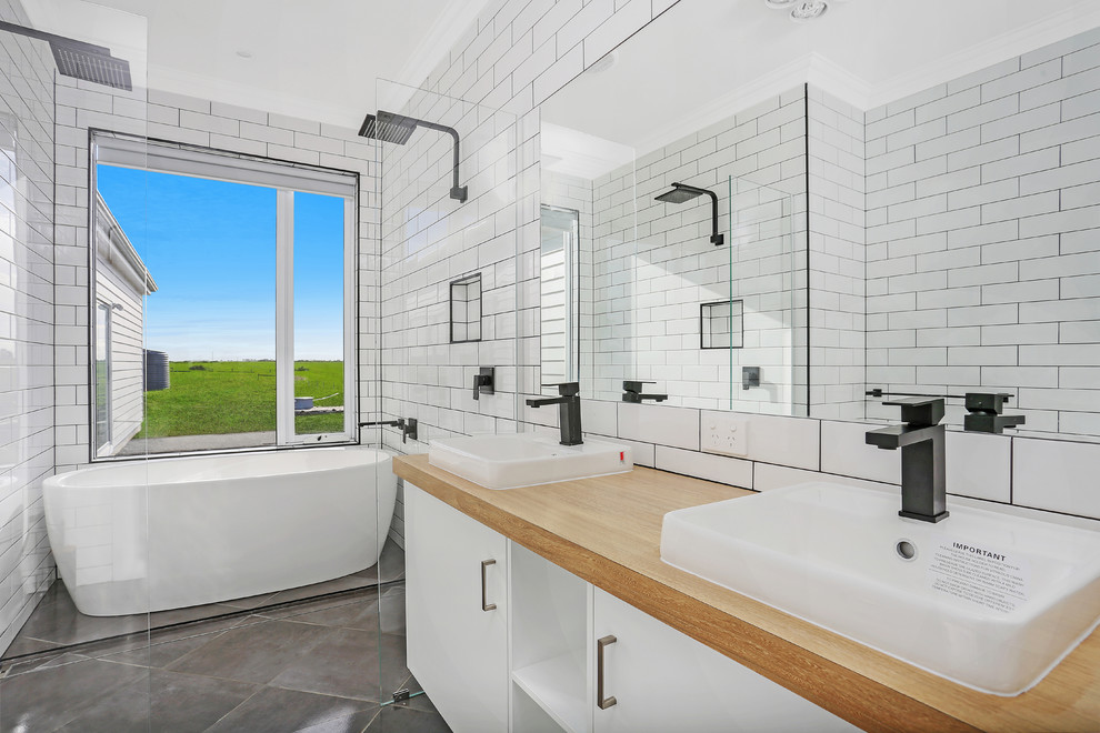 Inspiration for a mid-sized industrial master bathroom in Melbourne with white cabinets, a freestanding tub, a double shower, a one-piece toilet, white tile, subway tile, white walls, ceramic floors and laminate benchtops.