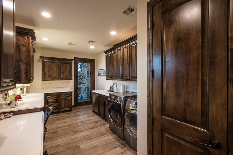 This is an example of a large country u-shaped utility room in Phoenix with an undermount sink, raised-panel cabinets, dark wood cabinets, quartz benchtops, beige walls, medium hardwood floors, a side-by-side washer and dryer, brown floor and turquoise benchtop.