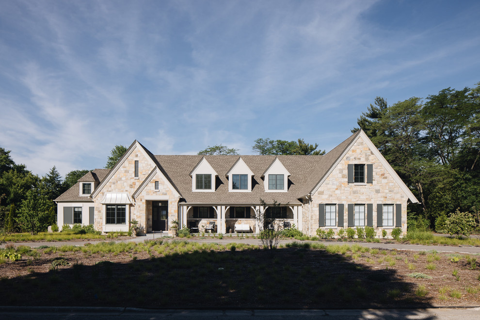 Idées déco pour une façade de maison beige en pierre à un étage avec un toit marron.