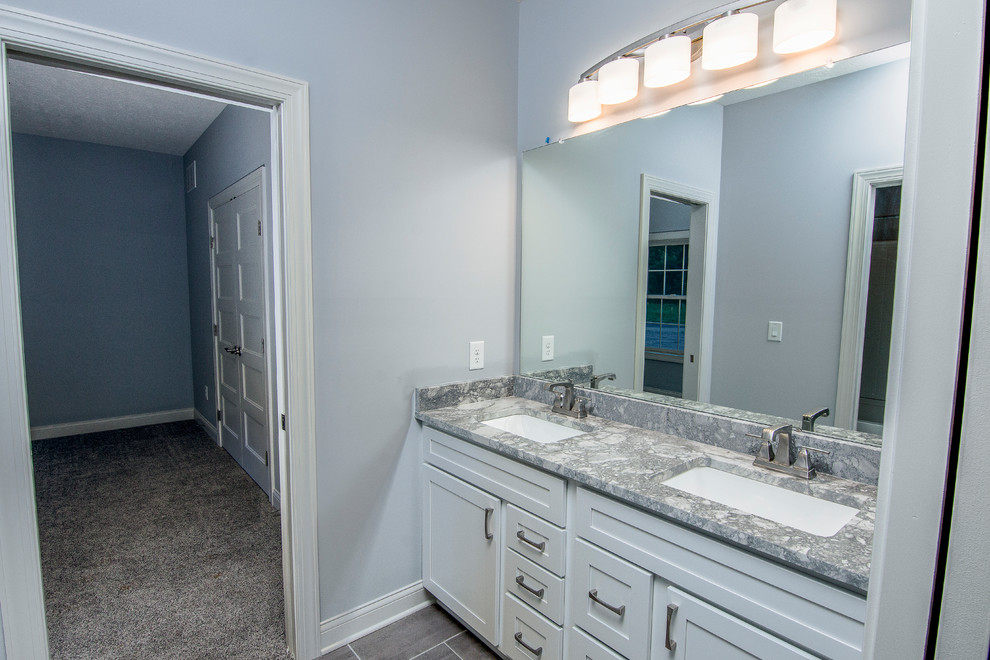 This is an example of a transitional bathroom in Columbus with shaker cabinets, white cabinets, a drop-in tub, an alcove shower, gray tile, white tile, subway tile, green walls, porcelain floors, an undermount sink, marble benchtops, grey floor and a sliding shower screen.