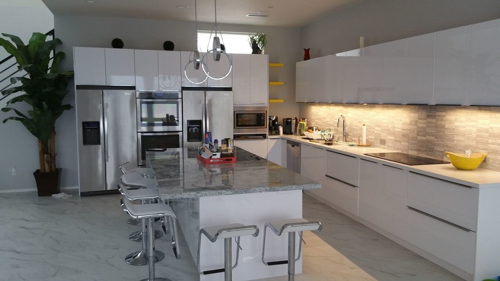 Inspiration for a large modern l-shaped white floor open concept kitchen remodel with an undermount sink, flat-panel cabinets, white cabinets, solid surface countertops, stainless steel appliances, an island and white countertops