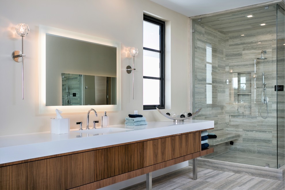This is an example of a large contemporary master bathroom in Orange County with flat-panel cabinets, medium wood cabinets, a corner shower, white walls, an integrated sink, grey floor, a hinged shower door, white benchtops, porcelain floors and engineered quartz benchtops.