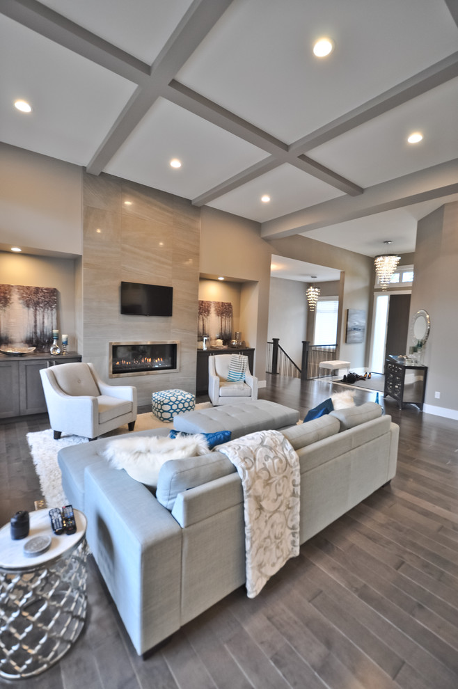 This is an example of a mid-sized transitional open concept living room in Edmonton with grey walls, light hardwood floors, a standard fireplace, a tile fireplace surround, a freestanding tv and brown floor.