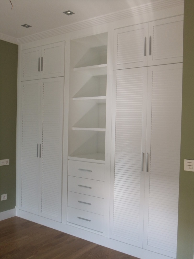 Design ideas for a mid-sized transitional gender-neutral built-in wardrobe in Other with white cabinets and medium hardwood floors.