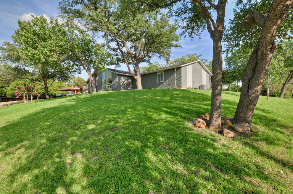 This is an example of a mid-sized midcentury one-storey brick grey exterior in Dallas with a gable roof.
