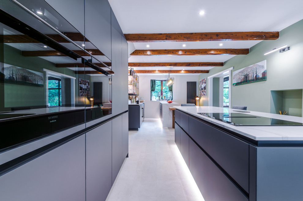 Medium sized contemporary galley open plan kitchen in Manchester with a built-in sink, flat-panel cabinets, grey cabinets, quartz worktops, glass sheet splashback, stainless steel appliances, an island, white worktops and a feature wall.