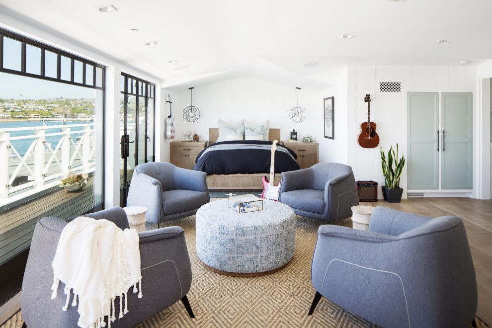 Photo of an expansive beach style guest bedroom in Orange County with white walls, light hardwood floors and beige floor.