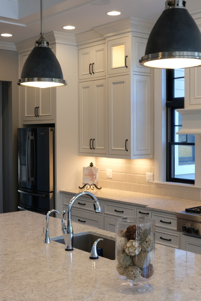 Inspiration for a large transitional l-shaped eat-in kitchen remodel with an undermount sink, recessed-panel cabinets, white cabinets, quartz countertops, white backsplash, stainless steel appliances and an island
