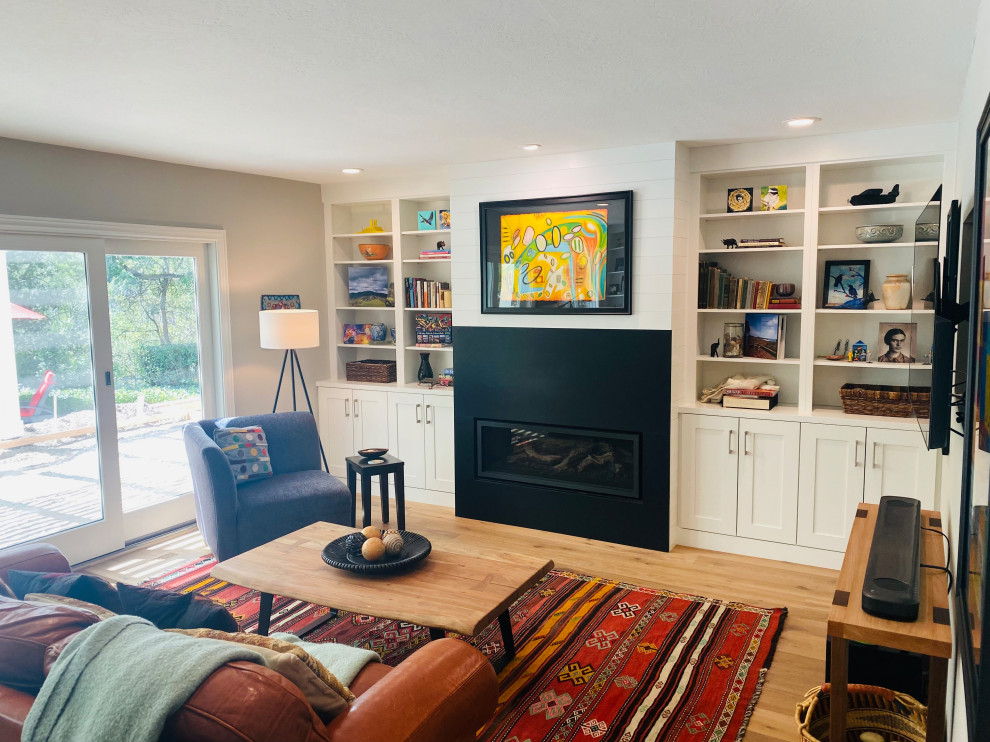 Large country enclosed family room in San Francisco with a library, white walls, light hardwood floors, a standard fireplace and a wall-mounted tv.