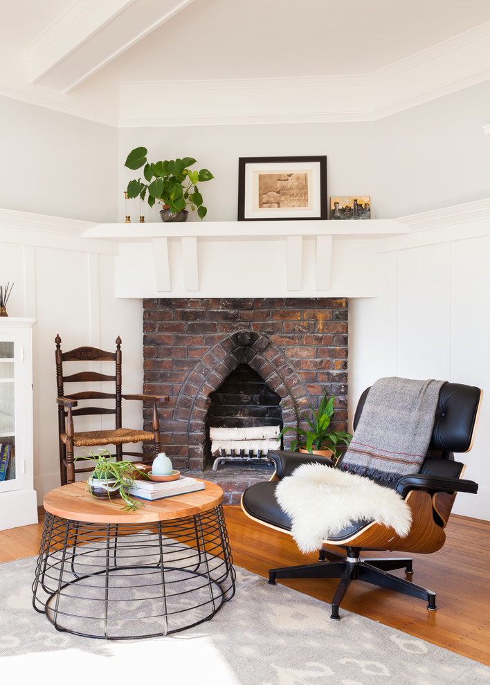 This is an example of a transitional living room in San Francisco with grey walls, medium hardwood floors, a corner fireplace and a brick fireplace surround.