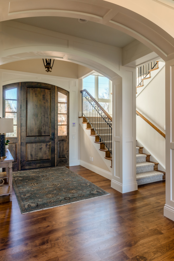 Inspiration for a large traditional front door in Denver with beige walls, medium hardwood flooring, a single front door, a dark wood front door, multi-coloured floors and a vaulted ceiling.