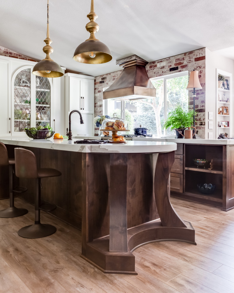 This is an example of a mid-sized traditional u-shaped open plan kitchen in Sacramento with a farmhouse sink, shaker cabinets, medium wood cabinets, quartz benchtops, coloured appliances, vinyl floors, with island, brown floor and white benchtop.