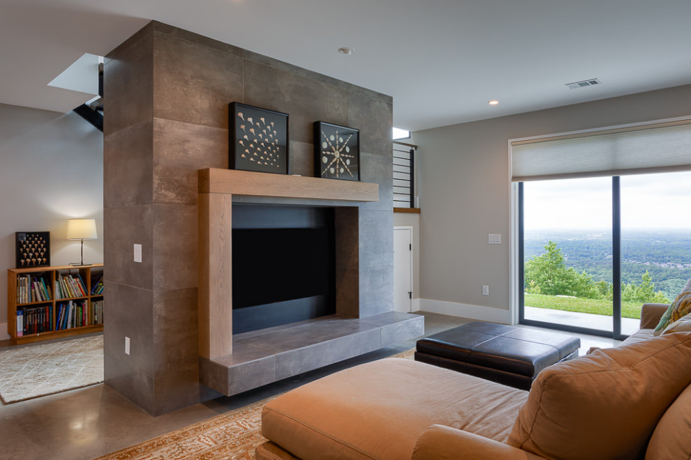 Réalisation d'une salle de séjour minimaliste avec un mur gris, sol en béton ciré, une cheminée standard, un manteau de cheminée en carrelage et un sol gris.