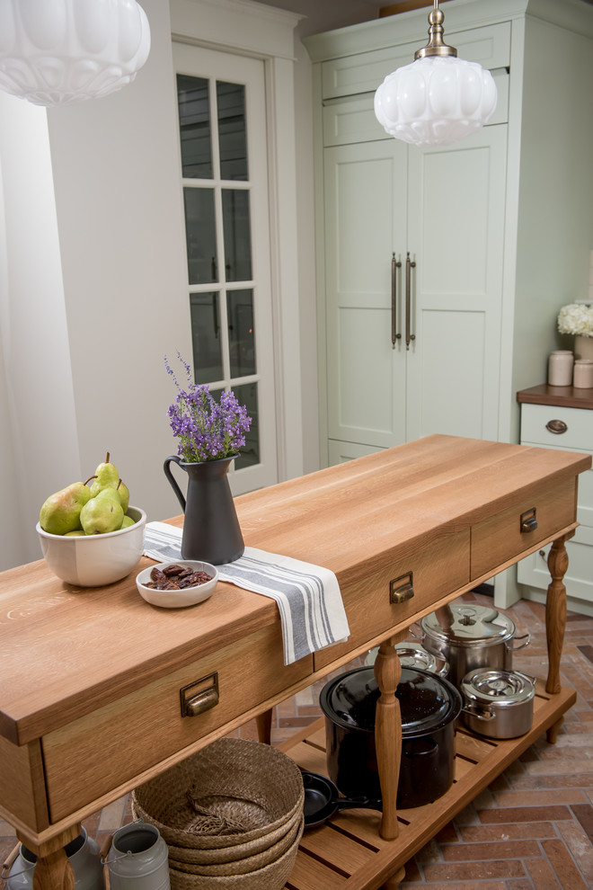 Farmhouse l-shaped porcelain tile enclosed kitchen photo with a farmhouse sink, recessed-panel cabinets, green cabinets, wood countertops, white backsplash, porcelain backsplash, colored appliances and an island