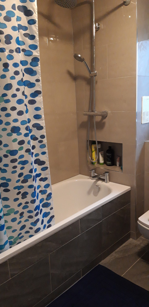 Photo of a medium sized contemporary family bathroom in London with flat-panel cabinets, white cabinets, a built-in bath, a double shower, a one-piece toilet, beige tiles, ceramic tiles, beige walls, ceramic flooring, a wall-mounted sink, grey floors, a shower curtain, a single sink and a freestanding vanity unit.