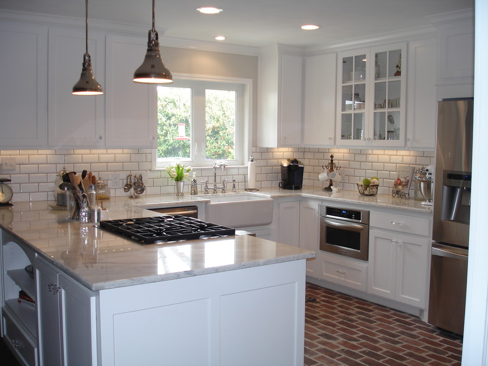 Photo of a large country u-shaped eat-in kitchen in Dallas with a farmhouse sink, shaker cabinets, white cabinets, marble benchtops, white splashback, subway tile splashback, stainless steel appliances, brick floors and with island.