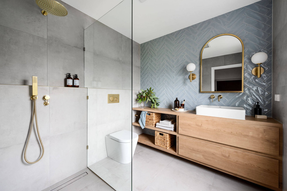 Photo of a mid-sized modern 3/4 bathroom in Melbourne with flat-panel cabinets, light wood cabinets, an open shower, a wall-mount toilet, blue tile, cement tile, grey walls, cement tiles, a vessel sink, wood benchtops, grey floor, an open shower, brown benchtops, a niche, a single vanity and a floating vanity.