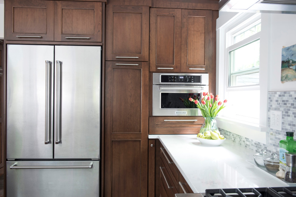 Kitchen - mid-sized transitional u-shaped vinyl floor and multicolored floor kitchen idea with an undermount sink, shaker cabinets, brown cabinets, quartz countertops, gray backsplash, marble backsplash, stainless steel appliances, no island and white countertops