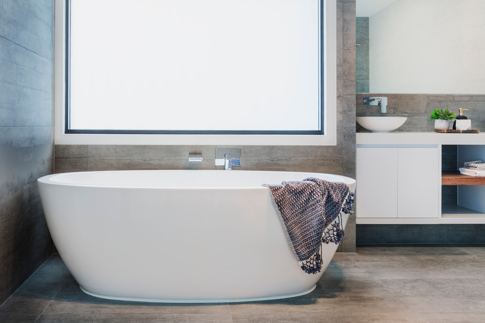 Mid-sized contemporary master bathroom in Melbourne with flat-panel cabinets, white cabinets, a freestanding tub, an alcove shower, a two-piece toilet, gray tile, cement tile, grey walls, concrete floors, a vessel sink and engineered quartz benchtops.