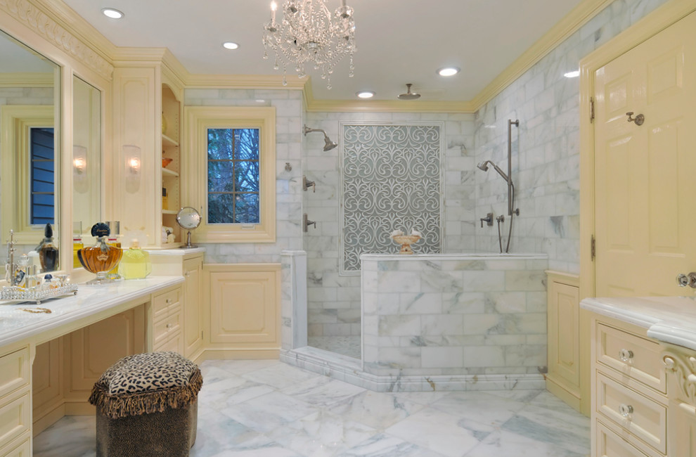 This is an example of a large traditional master bathroom in New York with yellow cabinets, a corner shower, white tile, stone tile, yellow walls, marble floors, a two-piece toilet, marble benchtops and recessed-panel cabinets.