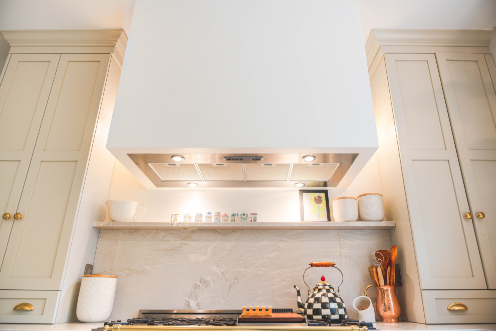 ワシントンD.C.にある高級な広いシャビーシック調のおしゃれなキッチン (エプロンフロントシンク、シェーカースタイル扉のキャビネット、白いキャビネット、珪岩カウンター、白いキッチンパネル、クオーツストーンのキッチンパネル、白い調理設備、淡色無垢フローリング、ベージュの床、ベージュのキッチンカウンター) の写真