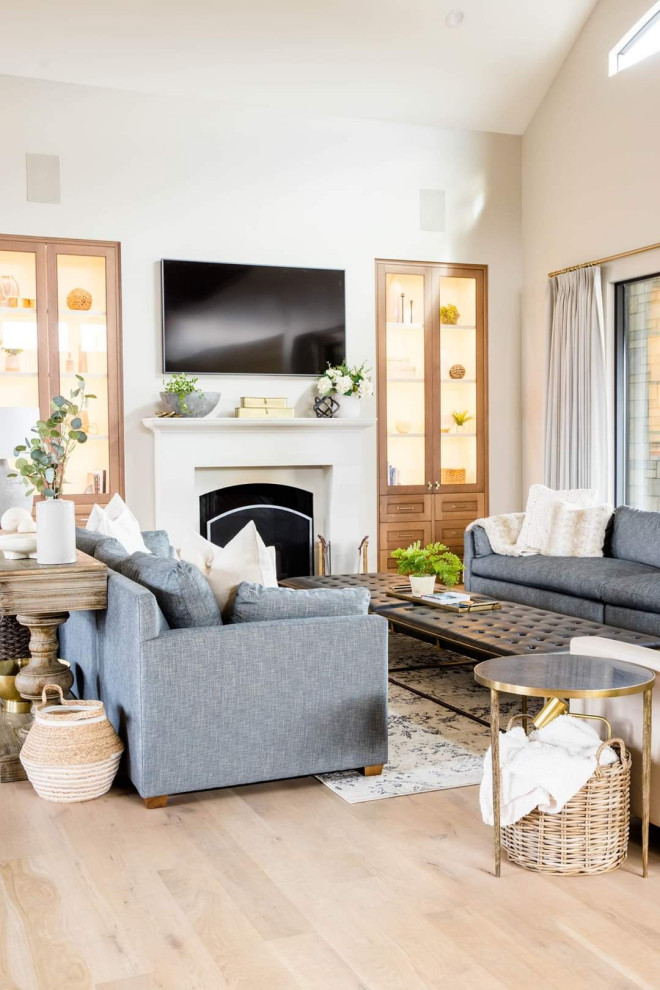 Inspiration for an expansive transitional living room in Kansas City with medium hardwood floors, a wood stove, a plaster fireplace surround and a wall-mounted tv.