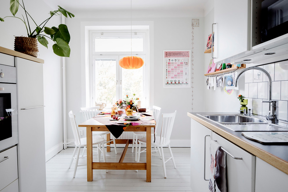 Mid-sized scandinavian kitchen/dining combo in Stockholm with white walls and white floor.