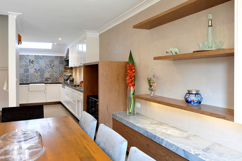 This is an example of a transitional u-shaped eat-in kitchen in Melbourne with a farmhouse sink, shaker cabinets, white cabinets, quartz benchtops, porcelain splashback, stainless steel appliances, concrete floors and no island.