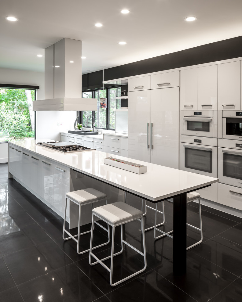 Design ideas for an expansive contemporary galley open plan kitchen in Minneapolis with flat-panel cabinets, white cabinets, white appliances, with island, a single-bowl sink, quartz benchtops, white splashback, porcelain floors, black floor and white benchtop.