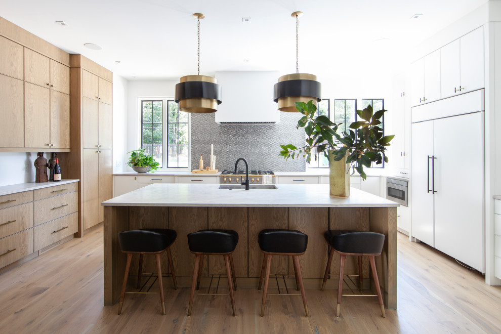 Inspiration for a contemporary u-shaped kitchen in Charlotte with an undermount sink, flat-panel cabinets, white cabinets, grey splashback, mosaic tile splashback, panelled appliances, medium hardwood floors, with island, brown floor and white benchtop.