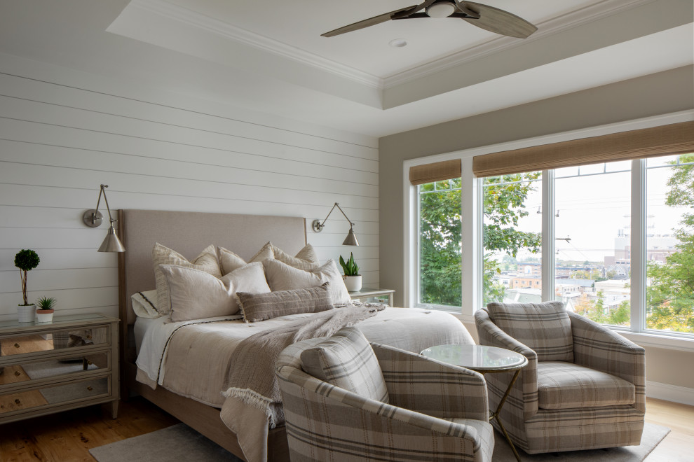Design ideas for a mid-sized transitional master bedroom in Milwaukee with beige walls, light hardwood floors, a standard fireplace, a tile fireplace surround, brown floor, recessed and planked wall panelling.