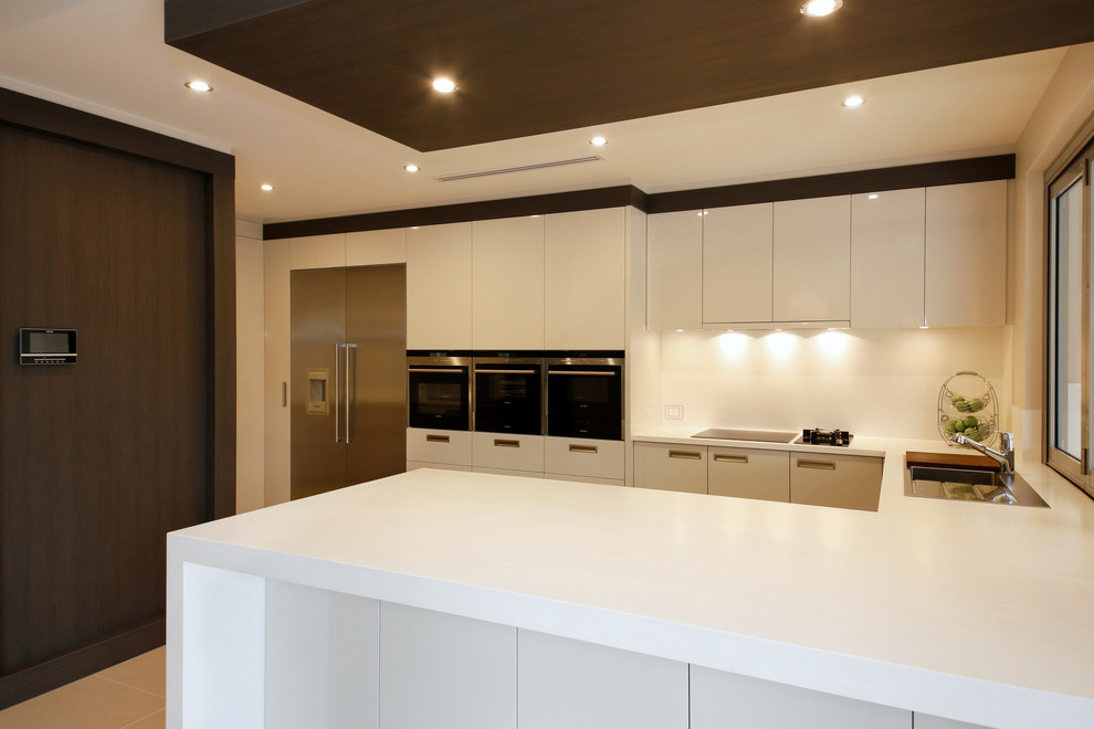 Design ideas for a large contemporary u-shaped kitchen pantry in Perth with a drop-in sink, solid surface benchtops, white splashback, stainless steel appliances, porcelain floors and with island.