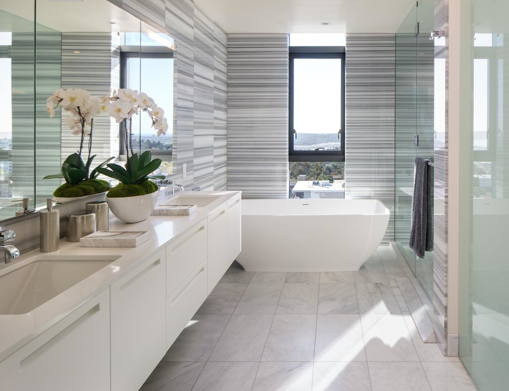 Contemporary bathroom in San Diego with flat-panel cabinets, white cabinets, a freestanding tub, gray tile, an undermount sink, white floor and white benchtops.