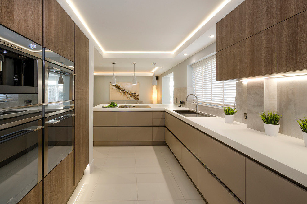 Design ideas for a large modern l-shaped kitchen in Devon with a double-bowl sink, flat-panel cabinets, laminate benchtops, grey splashback, porcelain splashback, stainless steel appliances, porcelain floors and a peninsula.