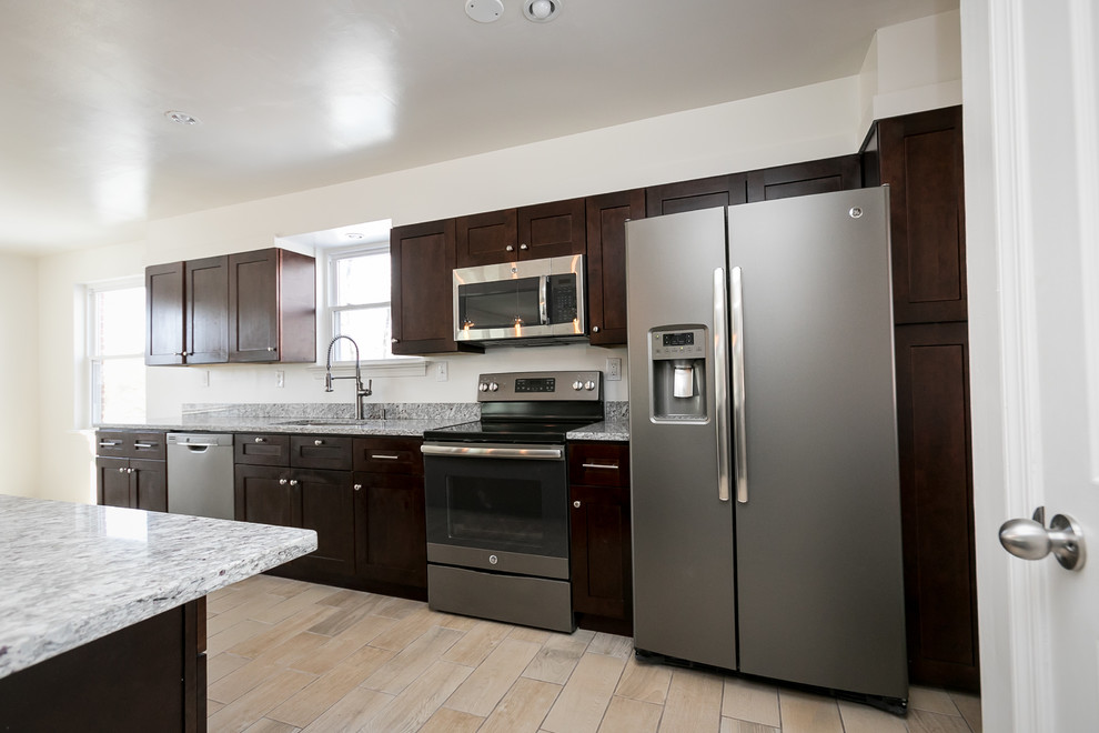 Open concept kitchen - mid-sized transitional galley porcelain tile and beige floor open concept kitchen idea in DC Metro with an undermount sink, shaker cabinets, dark wood cabinets, granite countertops, gray backsplash, stainless steel appliances, an island and gray countertops