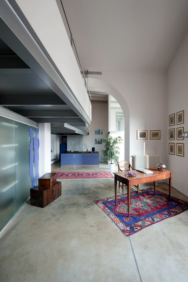 Photo of a large eclectic home office in Milan with white walls and concrete floors.