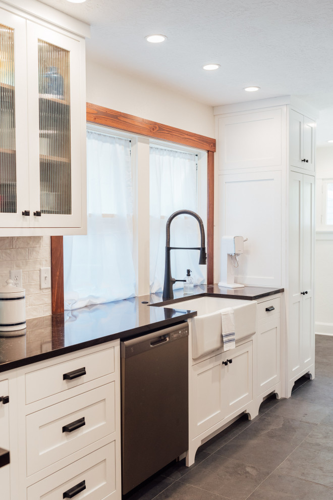 Example of a small arts and crafts galley slate floor and black floor eat-in kitchen design in Salt Lake City with a farmhouse sink, shaker cabinets, white cabinets, quartzite countertops, white backsplash, ceramic backsplash, black appliances, a peninsula and black countertops