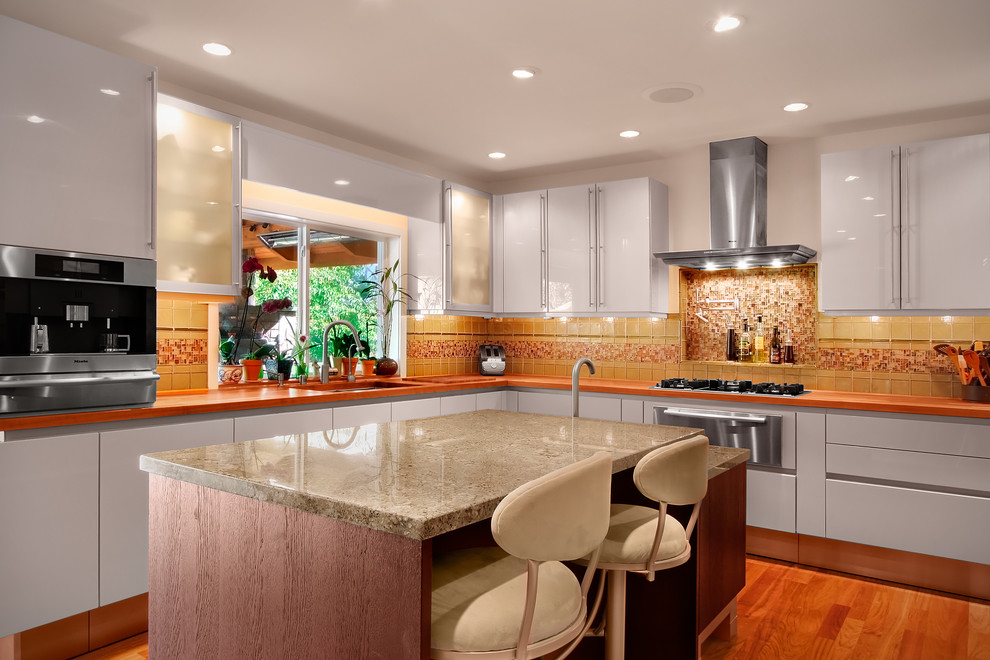 Inspiration for a contemporary kitchen in Seattle with glass tile splashback, stainless steel appliances, yellow splashback, flat-panel cabinets and white cabinets.