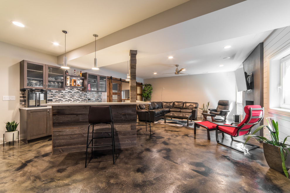 Inspiration for a large eclectic fully buried basement in Chicago with a home bar, concrete floors, a standard fireplace, a concrete fireplace surround and multi-coloured floor.