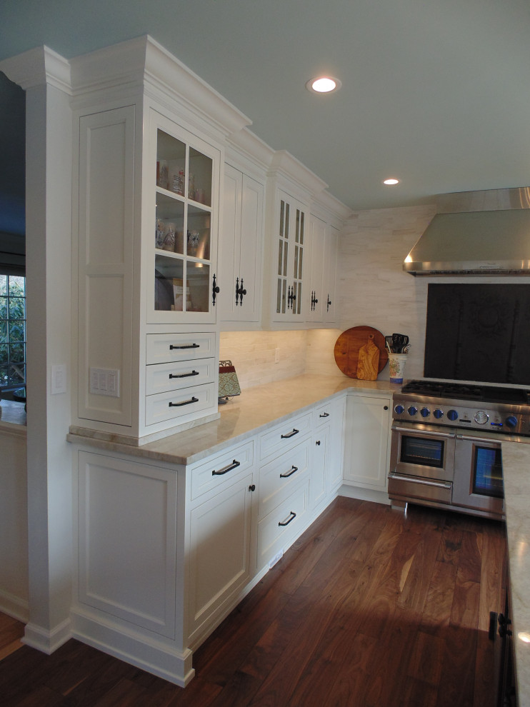 Example of a large transitional u-shaped medium tone wood floor and brown floor eat-in kitchen design with an undermount sink, recessed-panel cabinets, white cabinets, quartzite countertops, beige backsplash, subway tile backsplash, stainless steel appliances, an island and beige countertops