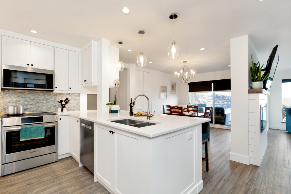 Inspiration for a mid-sized transitional u-shaped vinyl floor and beige floor eat-in kitchen remodel in Vancouver with a double-bowl sink, shaker cabinets, white cabinets, quartz countertops, blue backsplash, mosaic tile backsplash, stainless steel appliances, a peninsula and white countertops