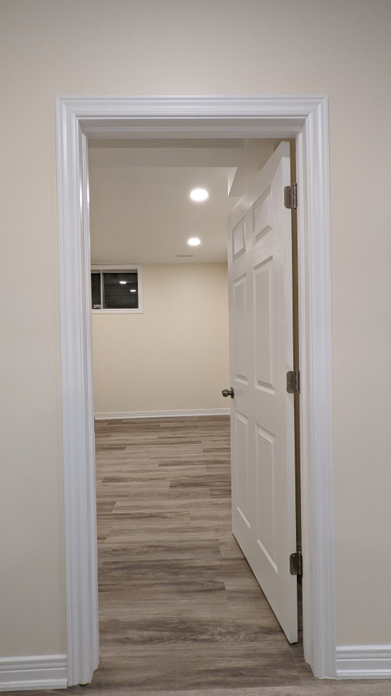 Basement - mid-sized transitional laminate floor and brown floor basement idea in Ottawa with white walls and no fireplace