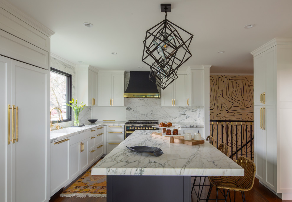 Photo of a large midcentury l-shaped kitchen in San Francisco with a drop-in sink, shaker cabinets, white cabinets, marble benchtops, white splashback, stone slab splashback, black appliances, dark hardwood floors, with island and brown floor.
