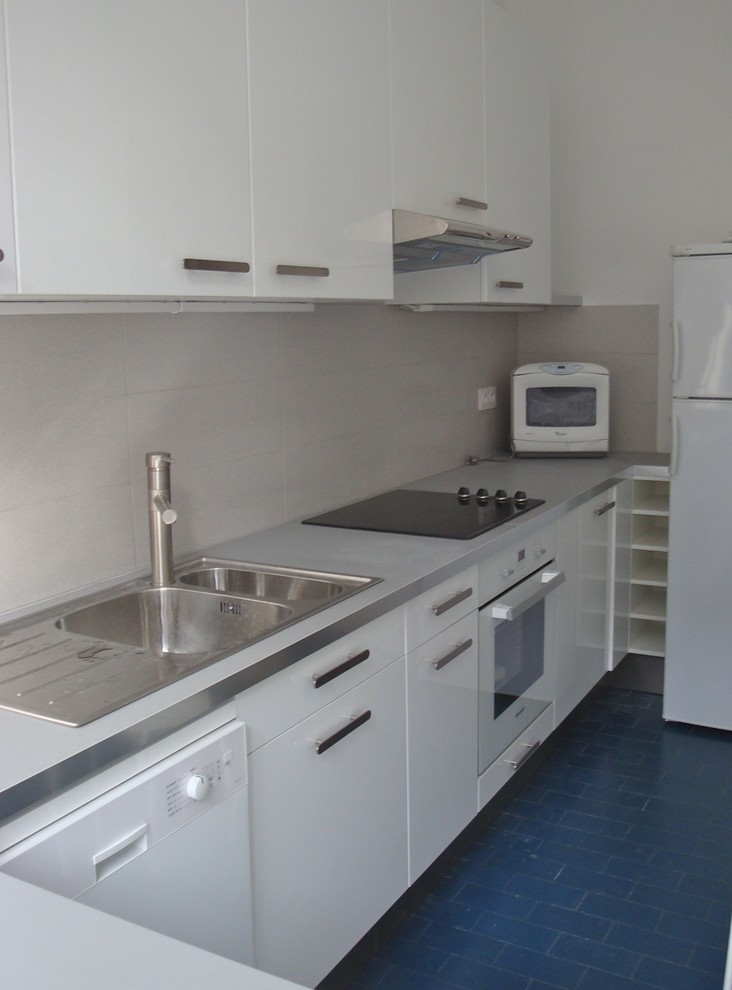 Aménagement de cuisine in L With un évier 2 bacs, un placard à porte affleurante, des portes de placard blanches, un plan de travail en stratifié, une crédence grise, un électroménager en acier inoxydable, un sol en carrelage de céramique, un sol bleu, une crédence en céramique and îlot.